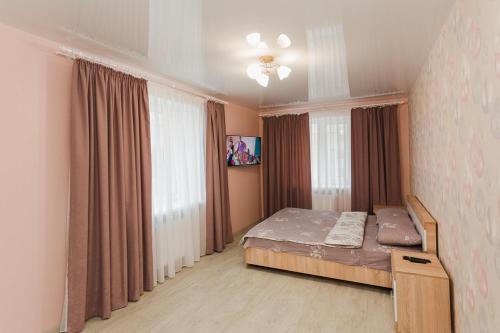 een slaapkamer met een bed en een raam met gordijnen bij Apart Prokof'yeva in Sumy