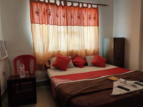 Schlafzimmer mit einem Bett mit roten Kissen und einem Fenster in der Unterkunft Hotel Grace in Agra