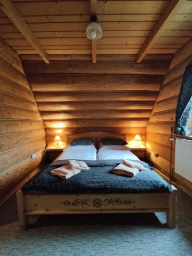 a bedroom with a bed in a wooden room at Domki Szwajnosówka in Witów