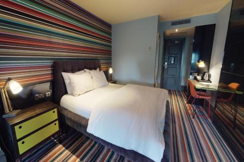 a bedroom with a bed with a striped wall at Village Hotel Wirral in Bromborough
