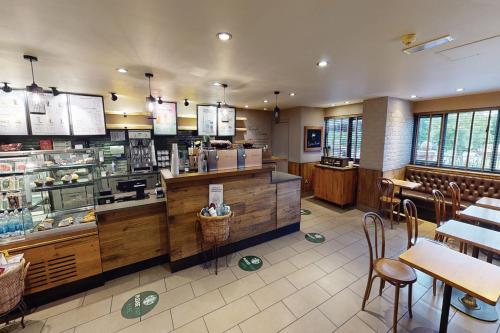 a restaurant with a counter and tables and chairs at Village Hotel Wirral in Bromborough