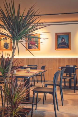 Un restaurante con mesas y sillas y una palmera. en Hotel Residence Dolcenero, en San Daniele del Friuli