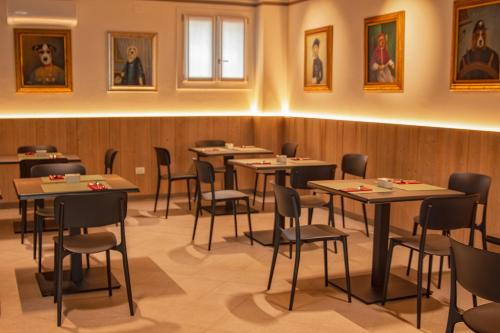 un comedor con mesas, sillas y cuadros en la pared en Hotel Residence Dolcenero, en San Daniele del Friuli