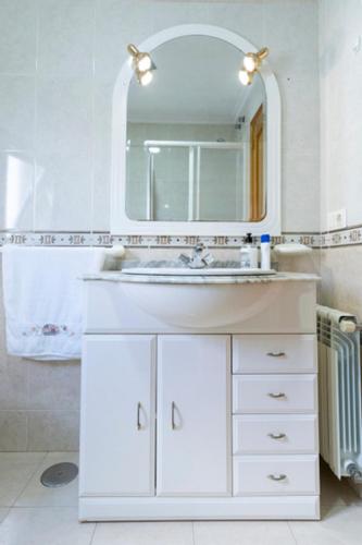 a white bathroom with a sink and a mirror at Playa de Llas in Foz