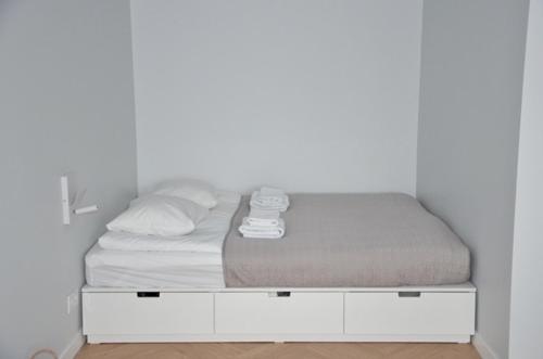 łóżko w pokoju z białą ścianą w obiekcie Vytautas Park Apartment w Mariampolu