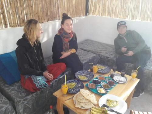 three people sitting on a couch with food on a table at Riad Isabele in Old Medina in Marrakech