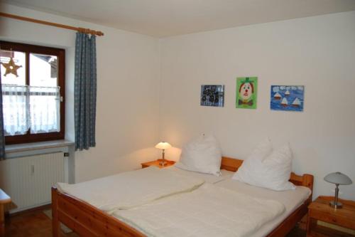 um quarto com uma cama com lençóis brancos e uma janela em Ferienwohnanlage Hochgern em Unterwössen