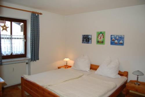 a bedroom with a bed with white sheets and a window at Ferienwohnanlage Hochgern in Unterwössen