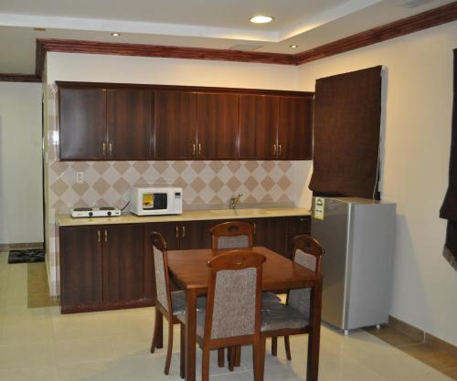 cocina con mesa, sillas y nevera en Nafa Serviced Apartments نافا للشقق المخدومة الدمام, en Dammam