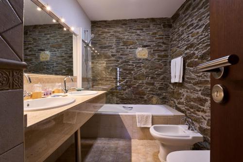 a bathroom with two sinks and a tub and a toilet at Lar da Mota Boutique Hotel in Arzúa