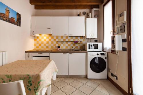 eine kleine Küche mit weißen Schränken und einem Tisch in der Unterkunft BellaMantova 3 in Mantua