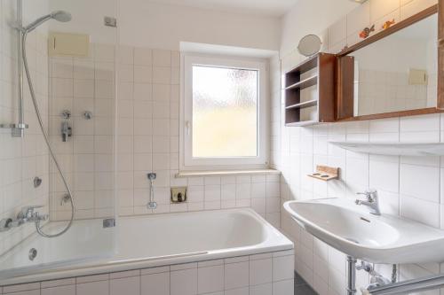 a white bathroom with a tub and a sink at Huflattich in Obermaiselstein