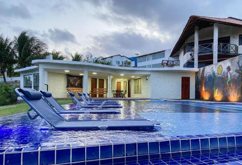 uma piscina com espreguiçadeiras em frente a uma casa em Rota do Mar em Maceió