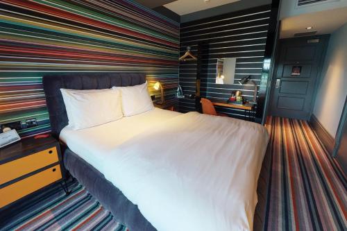 a bedroom with a large bed and a large window at Village Hotel London Watford in Elstree