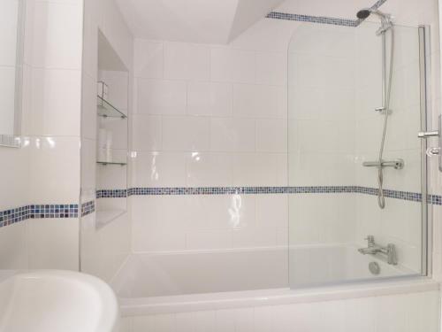 a white bathroom with a shower and a sink at Sally's Berth in Scarborough