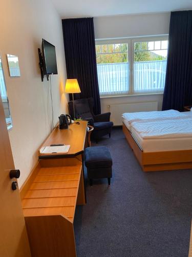 a hotel room with a bed and a desk and a bed and a chair at Altes Gasthaus Stover in Löningen