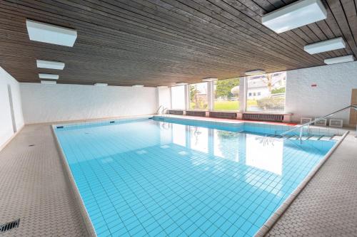 a large swimming pool with blue tiles in a building at Huflattich in Obermaiselstein