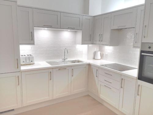 a white kitchen with white cabinets and a sink at Haworth Hideaway in Haworth