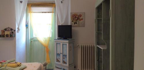 a room with a television on a dresser with a window at L'ANGOLINO, Casale vita nova in Manciano
