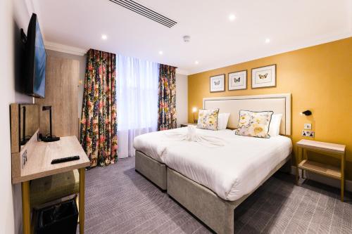 um quarto de hotel com uma cama e uma televisão de ecrã plano em Byron Hotel em Londres