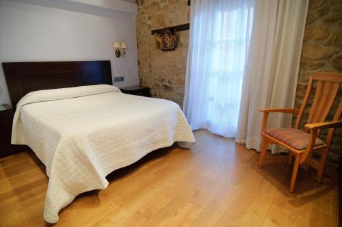 a bedroom with a bed and a chair and a window at Casa Rómulo in Duruelo de la Sierra