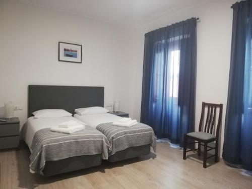 a bedroom with a bed with blue curtains and a chair at Cascais Bela House in Cascais