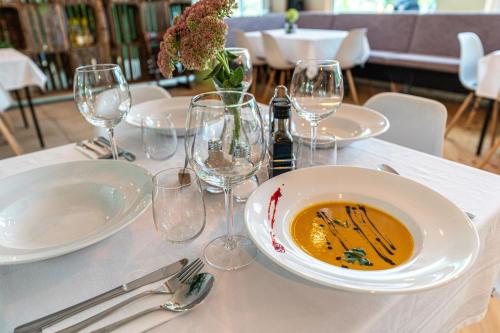 a table with a bowl of soup and wine glasses at Natura Ferienpark - Bungalows am Grimnitzsee Schorfheide in Althüttendorf