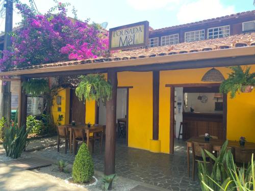 un restaurante con paredes amarillas, mesas y flores en Pousada do Mel, en Arraial d'Ajuda