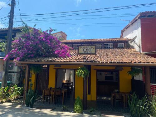 un restaurante con flores púrpuras en el techo de un edificio en Pousada do Mel, en Arraial d'Ajuda