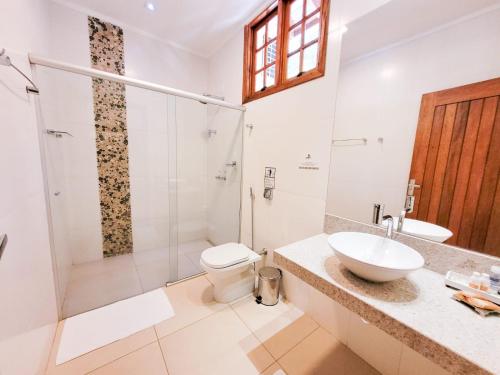 a bathroom with a shower and a toilet and a sink at Pousada Fazenda Peroba Rosa in Pedregulho