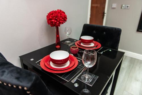a black table with red plates and wine glasses at Meridian Serviced Apartments in Bradford