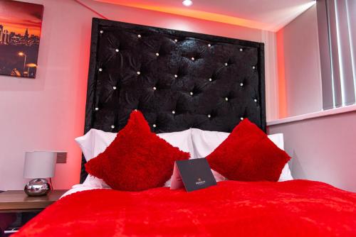 a bed with red pillows with a laptop on it at Meridian Serviced Apartments in Bradford