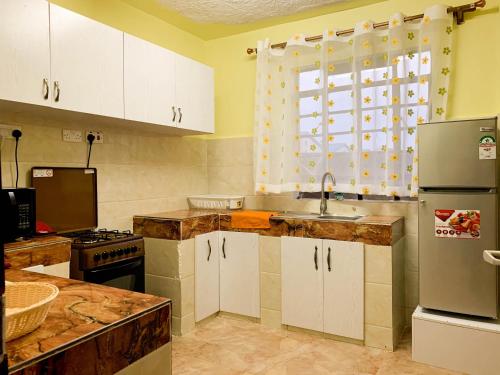 eine Küche mit weißen Schränken, einem Waschbecken und einem Fenster in der Unterkunft Easy Jkia Homestay in Nairobi