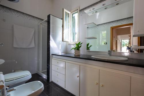 a bathroom with a sink and a toilet and a mirror at Villa Cielo e Terra by BarbarHouse in Torre Suda