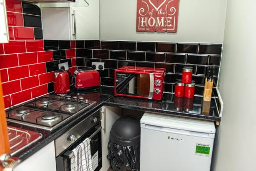 a small kitchen with red tiles on the wall at Meridian Serviced Apartments in Bradford