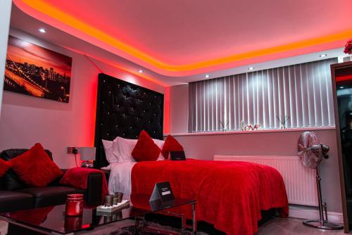 a bedroom with a red bed and a couch at Meridian Serviced Apartments in Bradford
