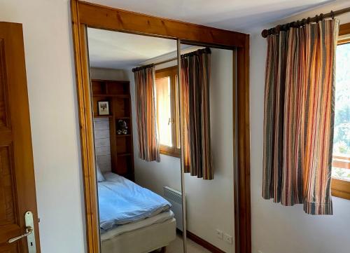 a mirror in a bedroom with a bed and a window at Le CAPRICORNE OLYMPIE 3 in Les Allues