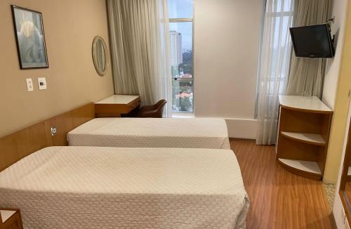 a hotel room with two beds and a window at Pampas Palace Hotel in São Bernardo do Campo