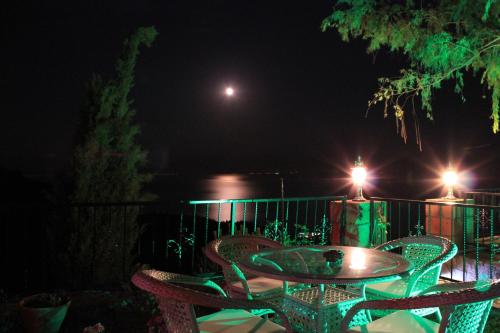 a patio table and chairs at night with a moon at Assos Kartal Yuvasi Hotel in Sazlı