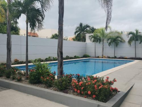 una piscina con palmeras y flores en Departamento privado con alberca cerca de la playa en Mazatlán