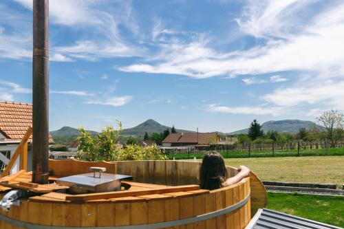 a woman is sitting in a wooden hot tub at Dandelion Vendégházak in Kisapáti