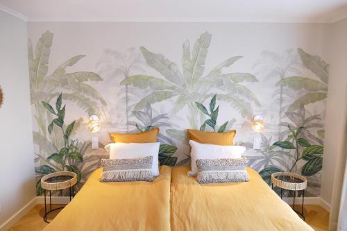 een slaapkamer met een bed met een muurschildering van palmbomen bij Les Agapanthes in Camphin-en-Pévèle