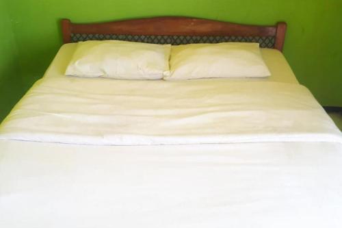 łóżko z białą pościelą i 2 poduszkami w obiekcie Ambar Tosari Homestay at Desa Wisata Bromo w mieście Pasuruan
