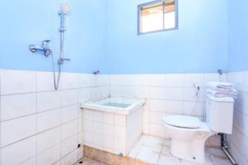 biała łazienka z toaletą i prysznicem w obiekcie Ambar Tosari Homestay at Desa Wisata Bromo w mieście Pasuruan