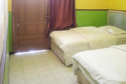a hotel room with two beds and a door at Ambar Tosari Homestay at Desa Wisata Bromo in Pasuruan
