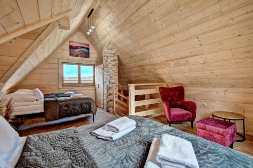 a log cabin with two beds and a red chair at Jędroskowe Chatki in Witów