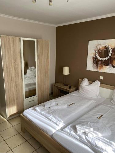 a bedroom with a large white bed and a mirror at Gaststätte Pütz in Siegen