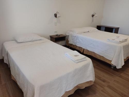 two beds in a room with white sheets at Betania in Paracas