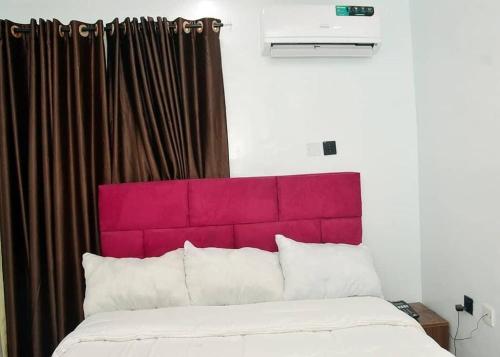 a bed with a red headboard in a room at Lords&ladies suites in Lagos