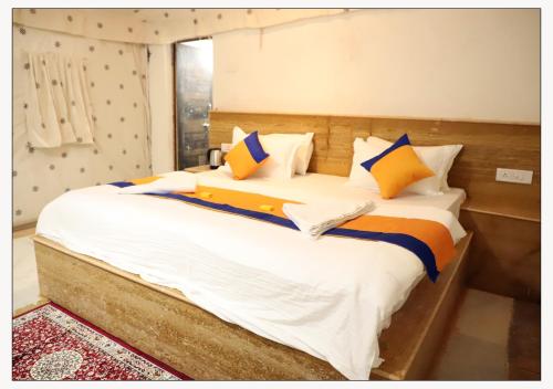 a bedroom with a large bed with yellow and blue pillows at Jaisalmer Desert Resort in Jaisalmer